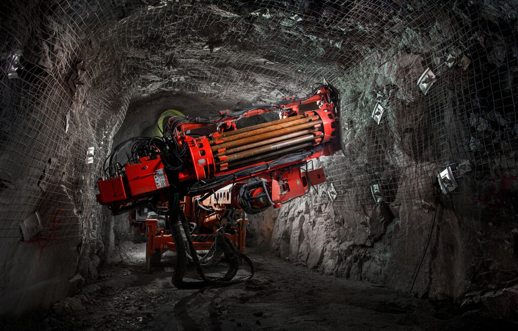 Underground drilling rig operating inside a reinforced tunnel.